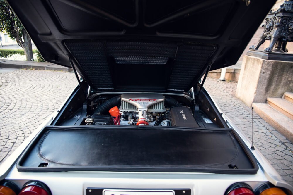 Classic car engine displayed in open trunk.