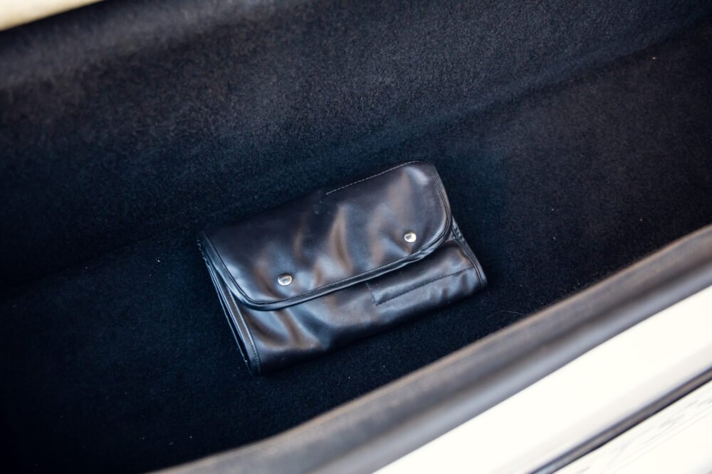 Black leather wallet on car trunk mat.