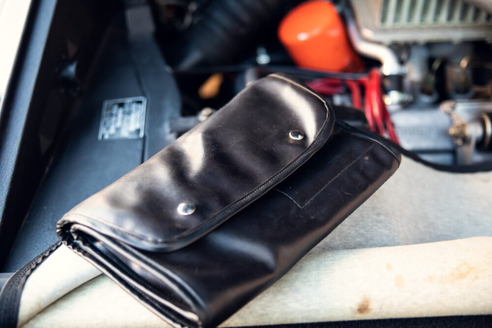 Black leather tool pouch in vintage car interior.
