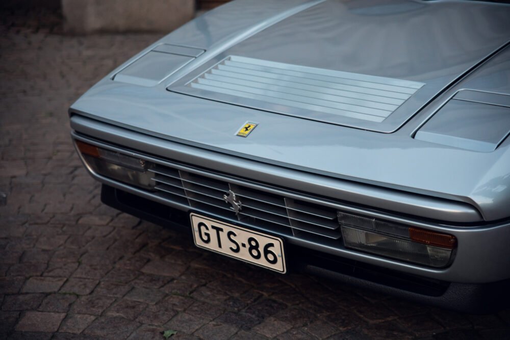 Close-up of vintage silver Ferrari with logo and grille.