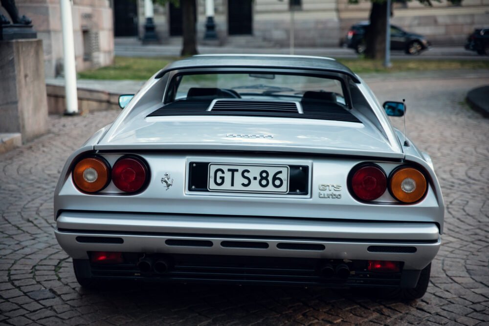 White Ferrari GTS Turbo parked on cobblestone street.