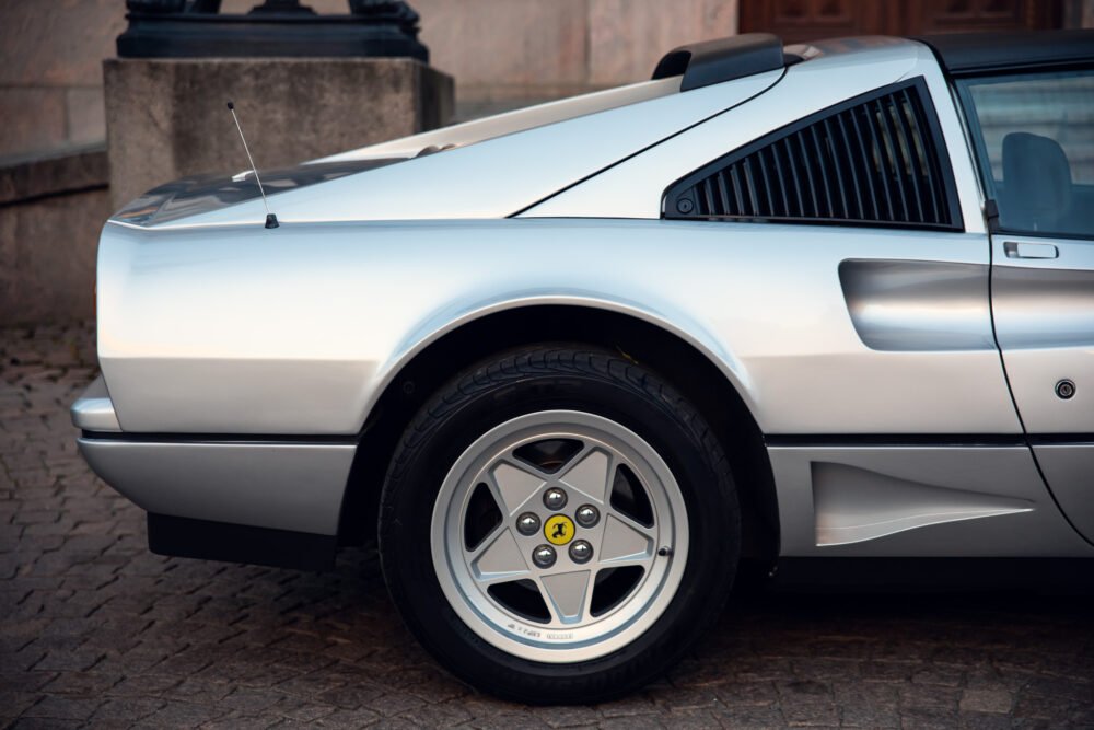 Close-up of classic silver sports car side and wheel.