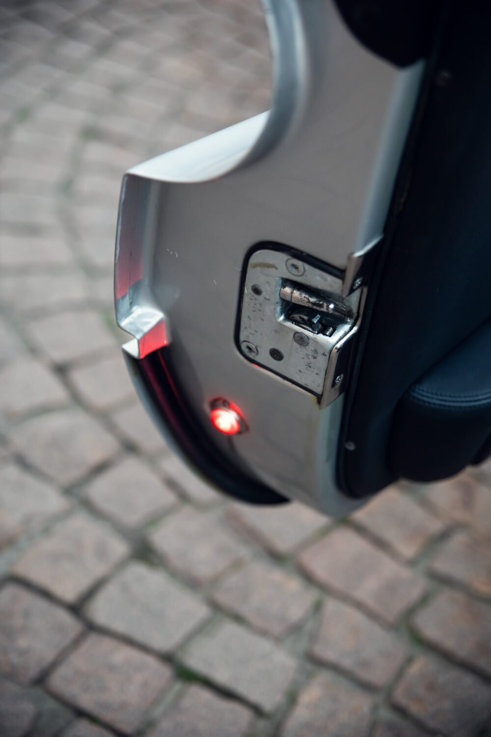 Close-up of electric scooter charging port with LED indicator.