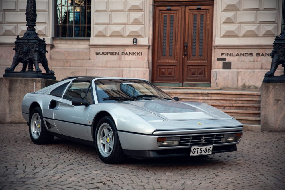 Silver Ferrari 308 parked in front of historic building.