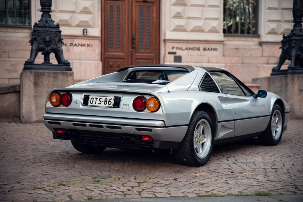 Silver vintage sports car outside historic building.