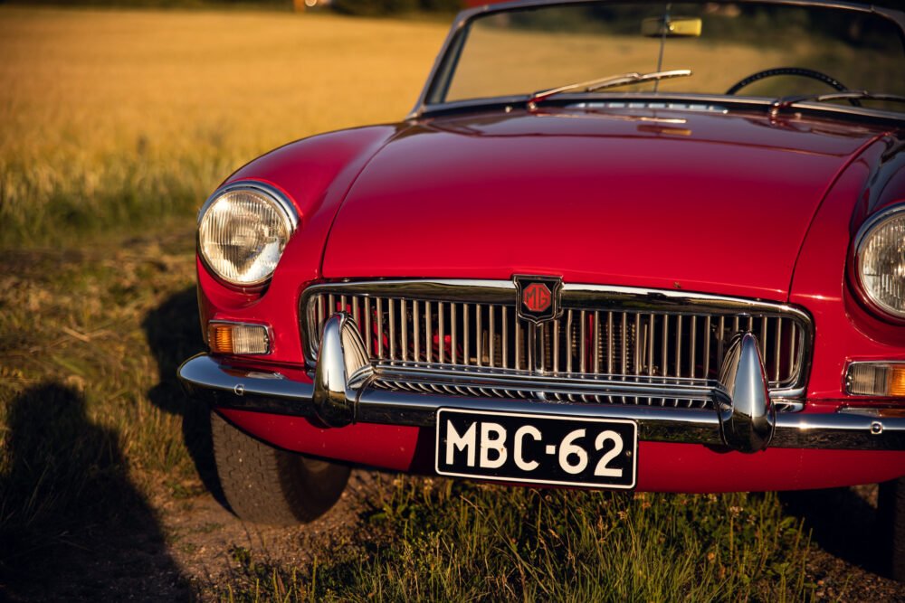 Red MG classic car in golden hour field.