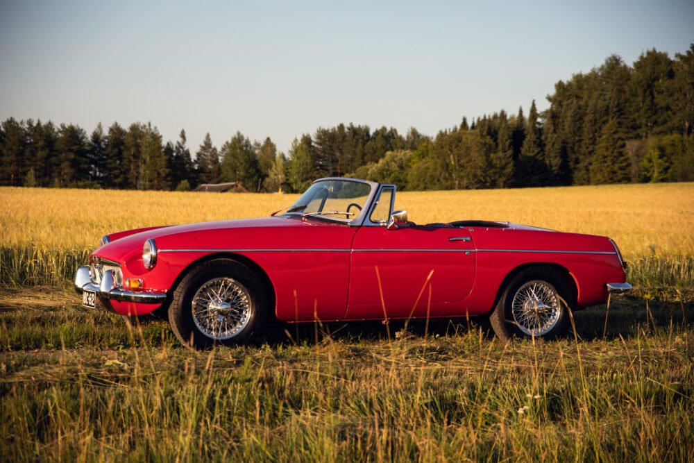 Red vintage convertible car in golden wheat field.