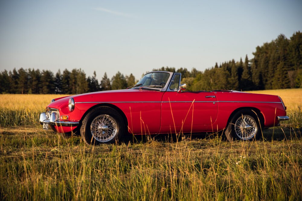 Red vintage convertible car in a golden field.
