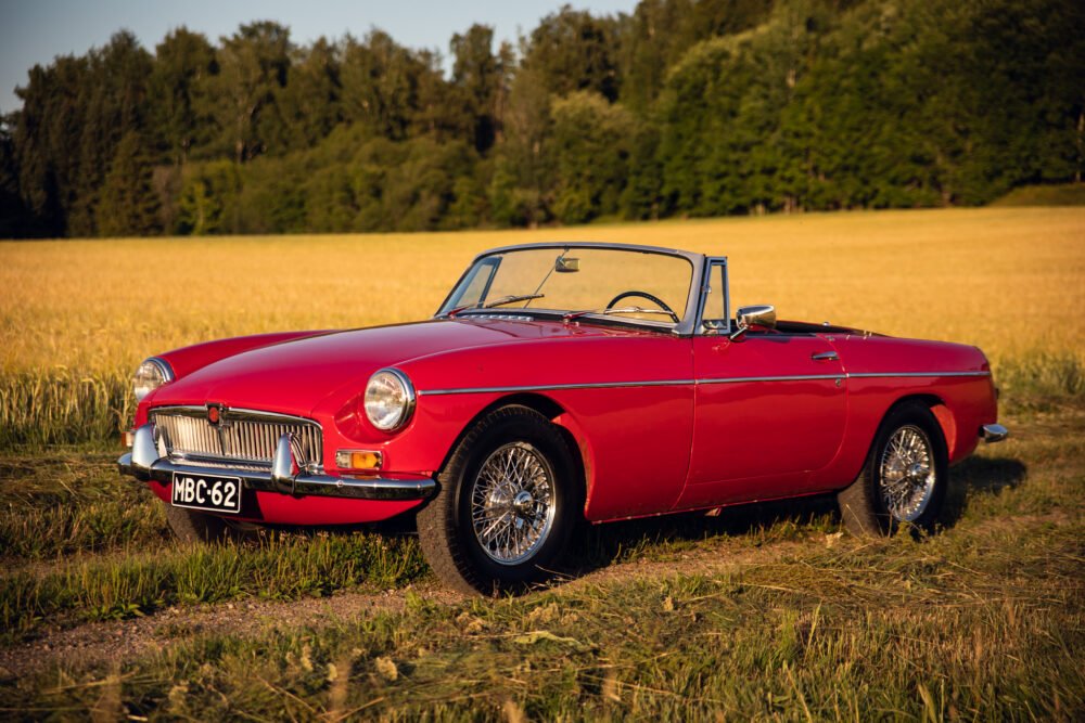 Red classic convertible car in golden field.