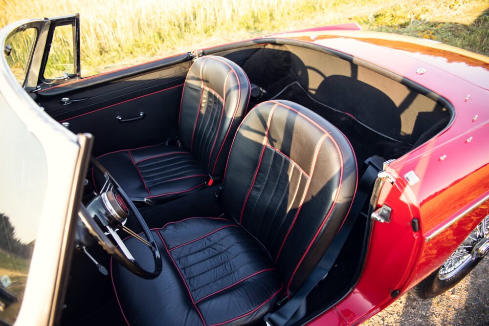 Vintage red convertible car interior, black leather seats.