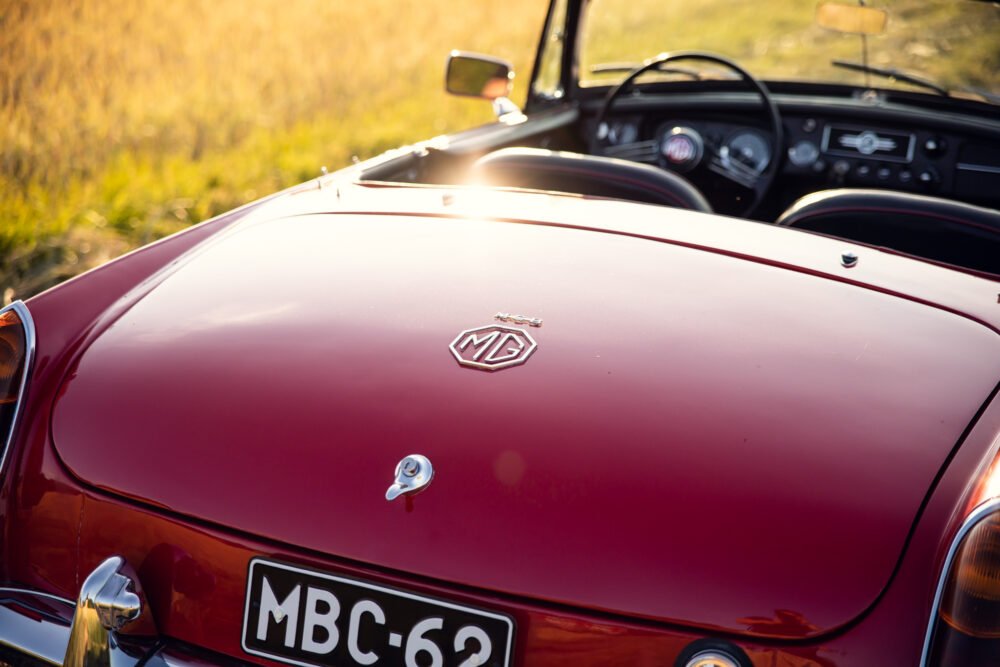 Vintage red MG car in golden hour sunlight.