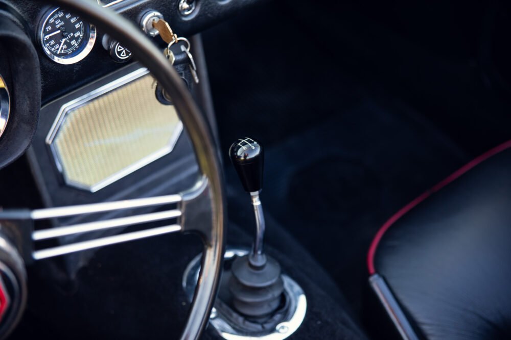 Vintage car's steering wheel and gear shift close-up.