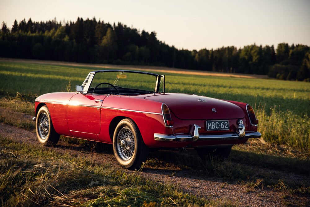 Vintage red convertible car in countryside setting.