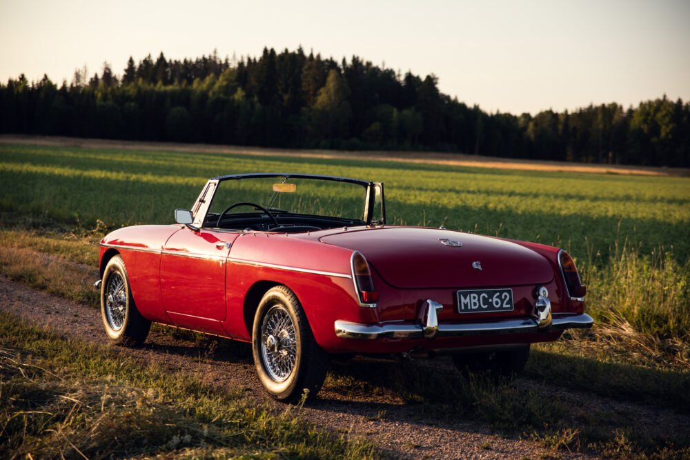 Red vintage convertible car in countryside at sunset.