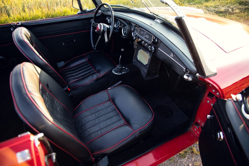Vintage red car interior with black leather seats.