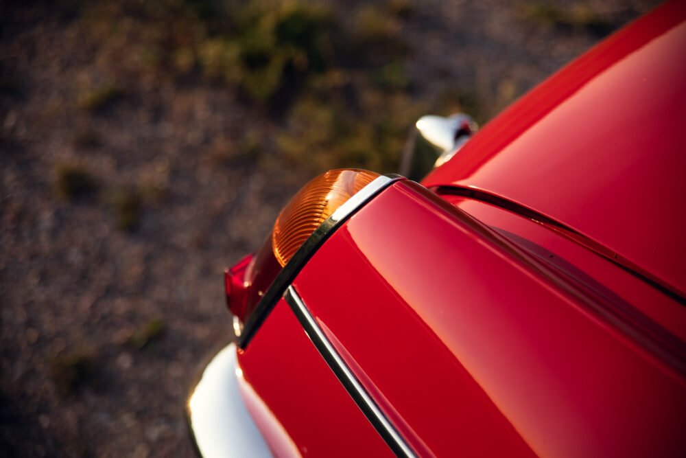 Close-up of red car's hood and signal light.