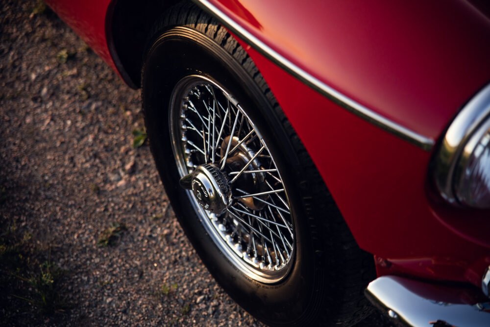Close-up of classic car's red body and wire wheel.