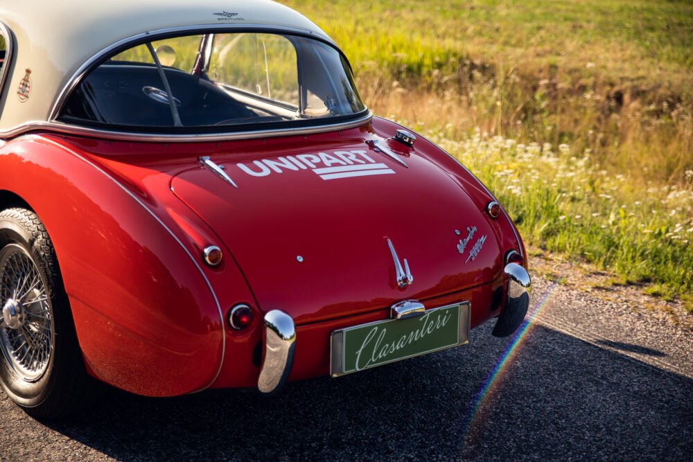 Vintage red sports car on sunny road.