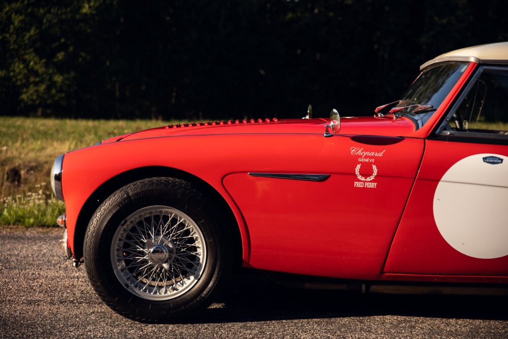 Red vintage sports car with chrome details and white stripe.