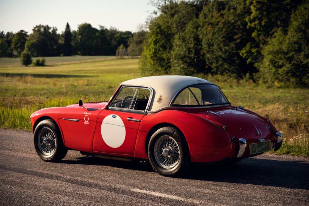 Vintage red sports car in rural setting.