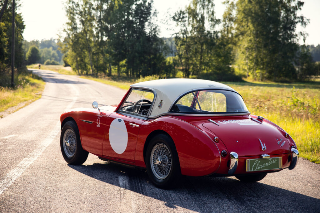 Vintage red sports car on sunny country road.