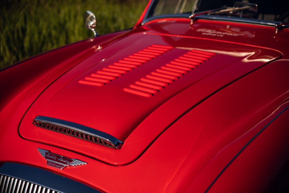 Close-up of red vintage Austin-Healey car hood.