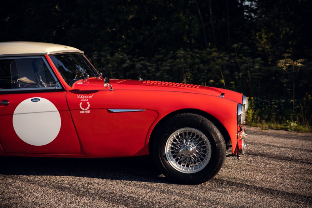 Vintage red sports car with racing decals outdoors.