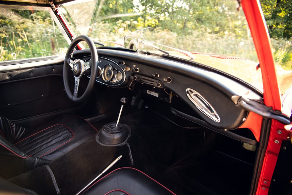 Vintage car interior with red accents and manual transmission.