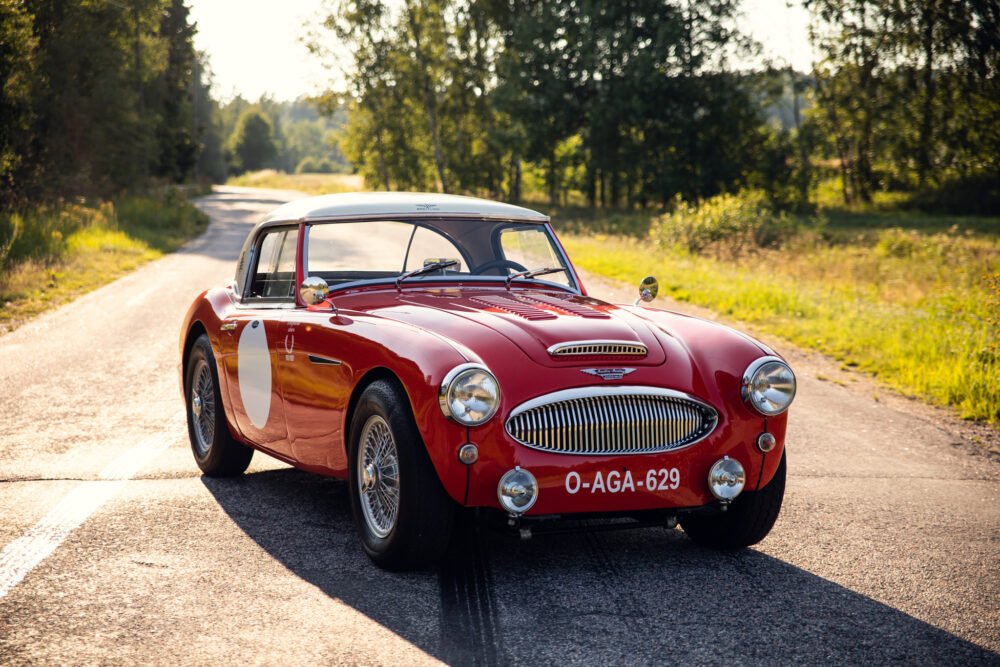 Vintage red sports car on sunny country road.