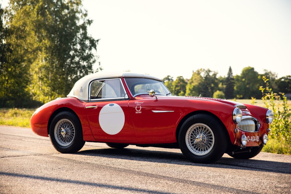 Vintage red sports car on sunny road.