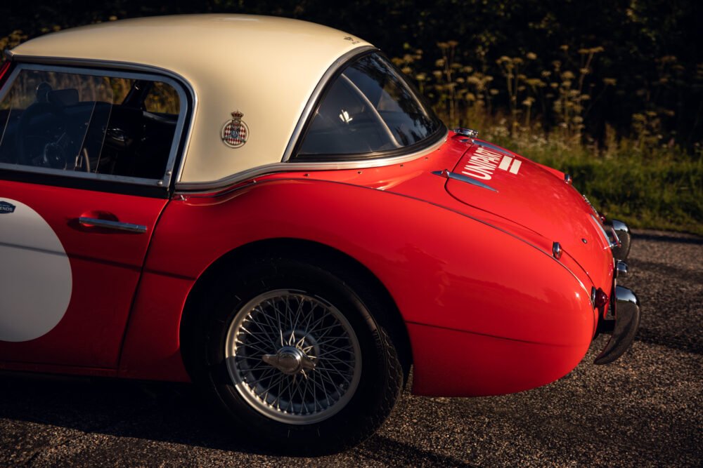 Vintage red and white sports car on road.