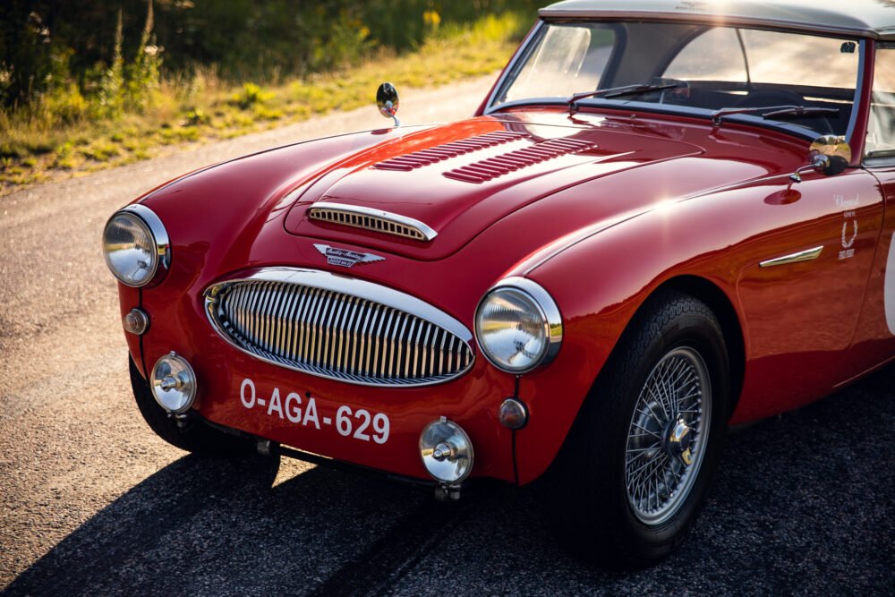 Vintage red sports car on sunny road.