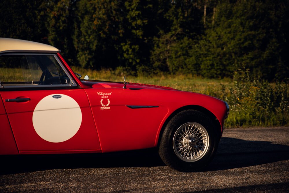 Red vintage sports car on countryside road.