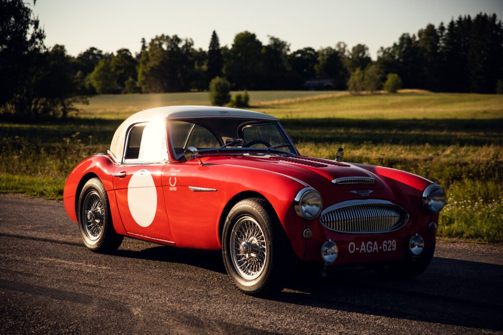 Vintage red sports car on countryside road at sunset.