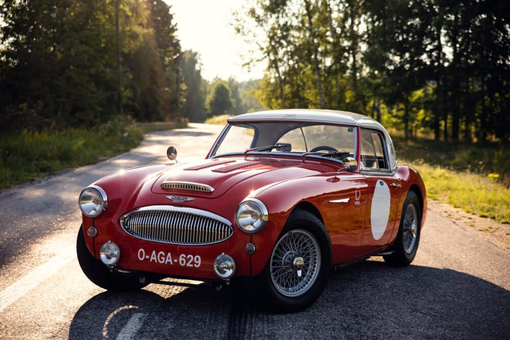 Classic red vintage car on sunny forest road.