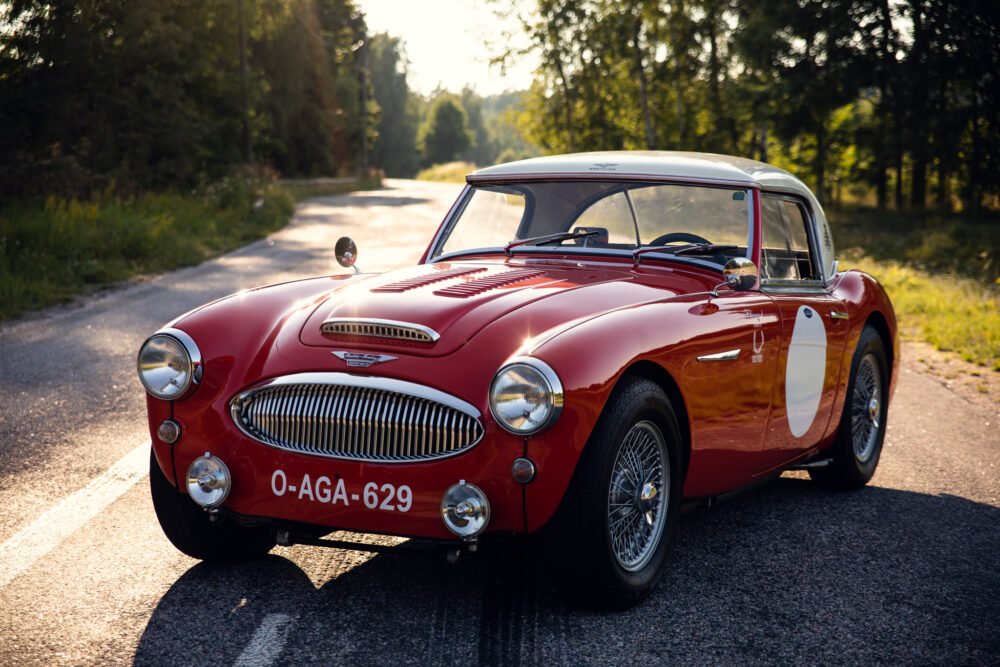 Vintage red Austin-Healey car on forest road.