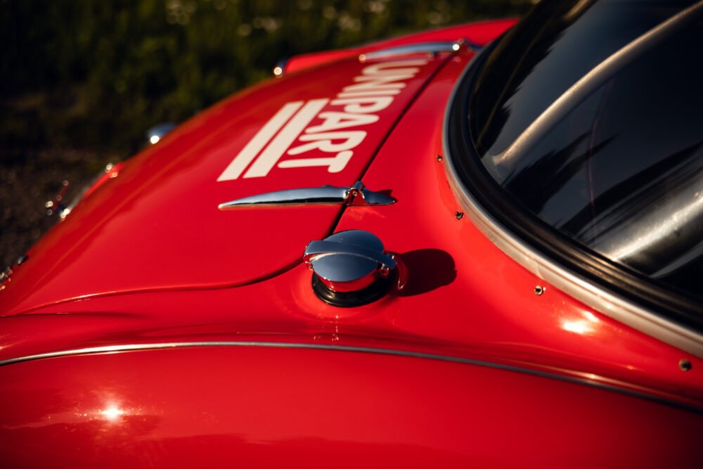 Red vintage car with sleek mirror and number decal.