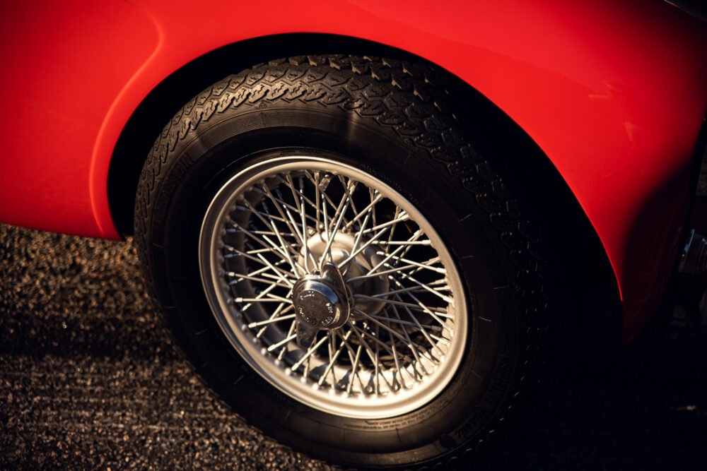 Close-up of red car's wire-spoke wheel.