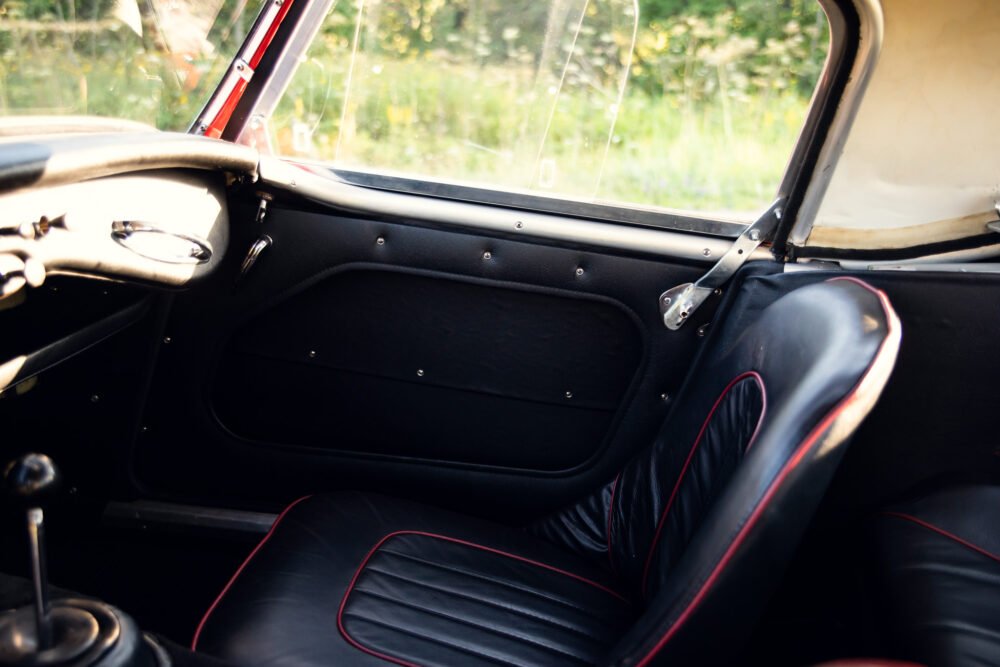 Vintage car interior with red detailed black seats.