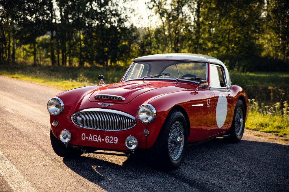 Vintage red Austin-Healey car on country road.