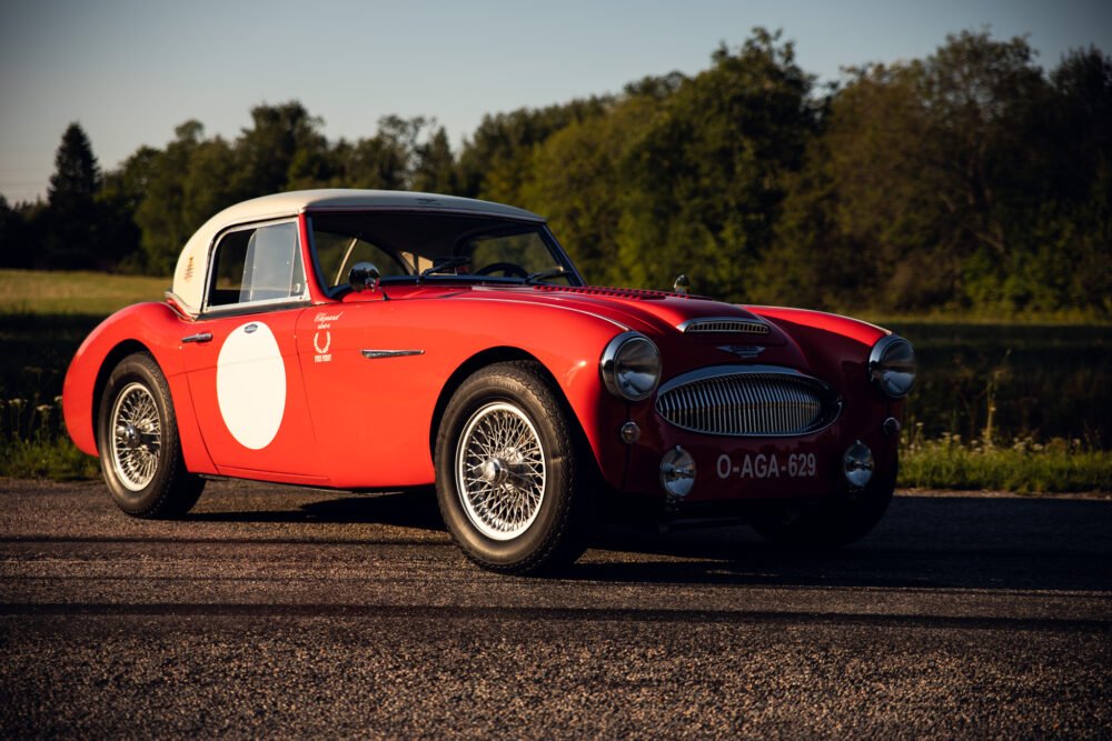 Vintage red Austin-Healey sports car on rural road.