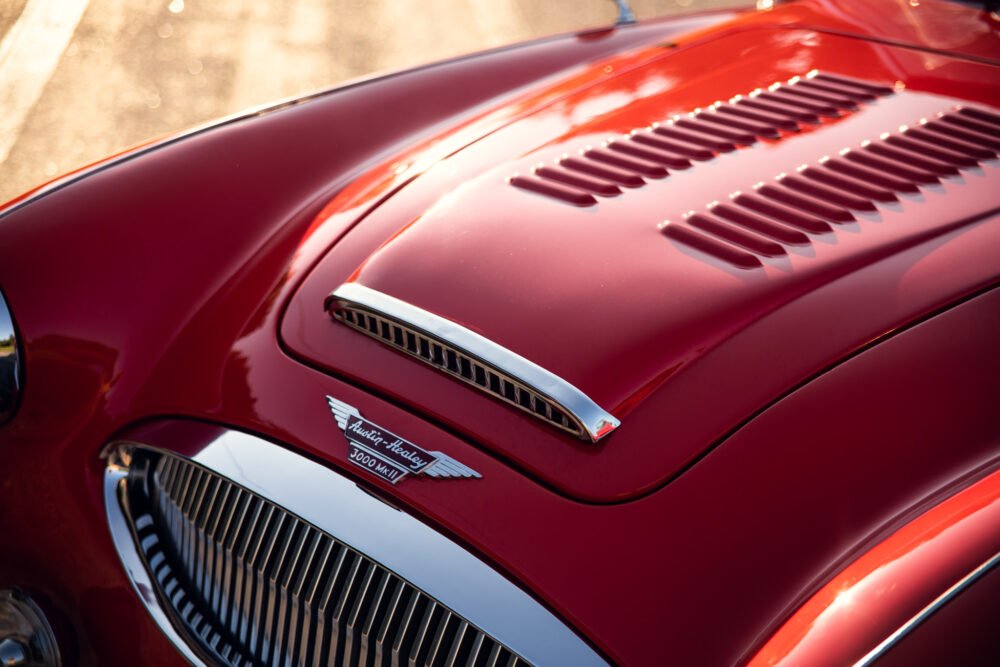 Close-up of vintage red Austin-Healey car hood.