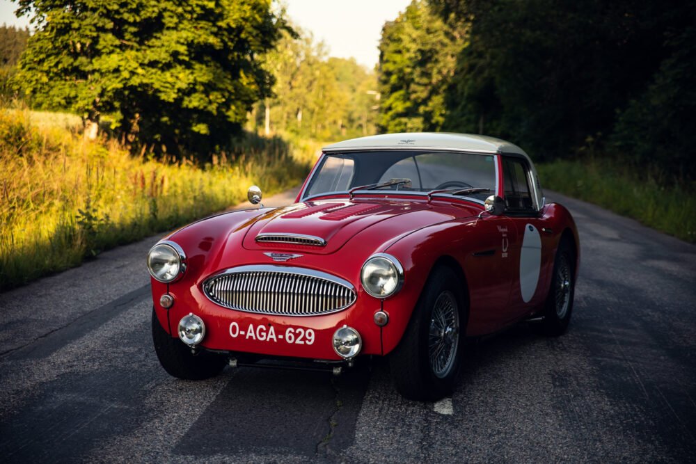 Vintage red Austin-Healey car on country road.