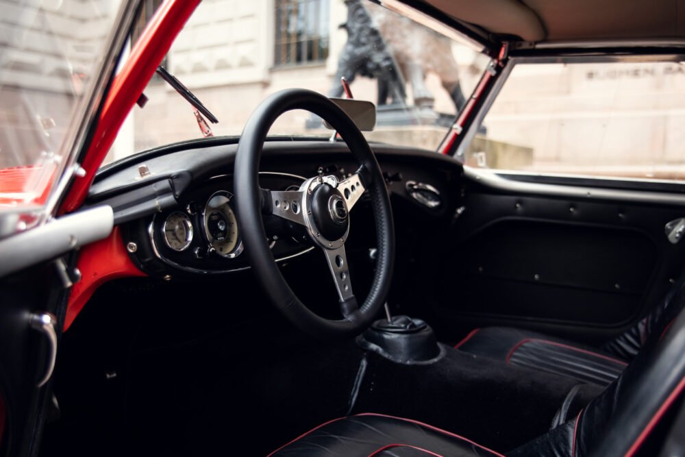 Vintage car interior with steering wheel and dashboard.