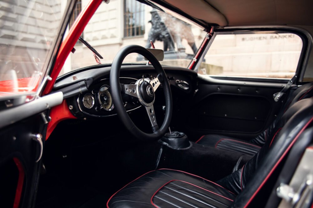 Vintage red car interior with steering wheel and dashboard.