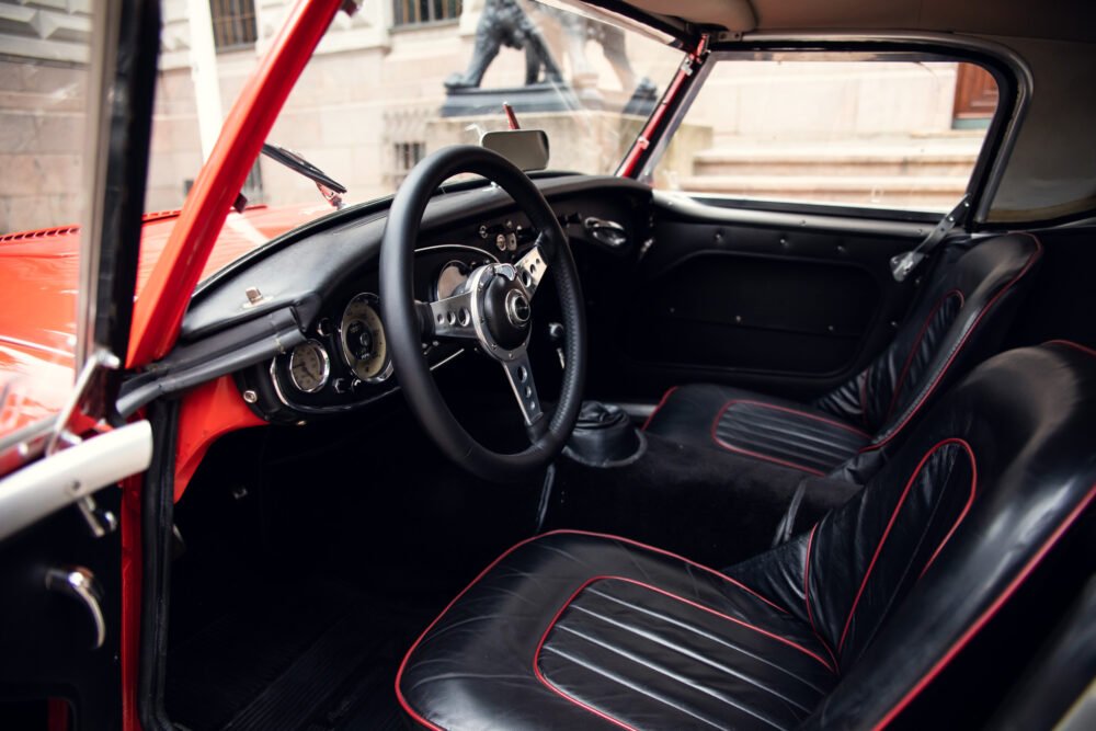 Vintage red car interior with black leather seats.