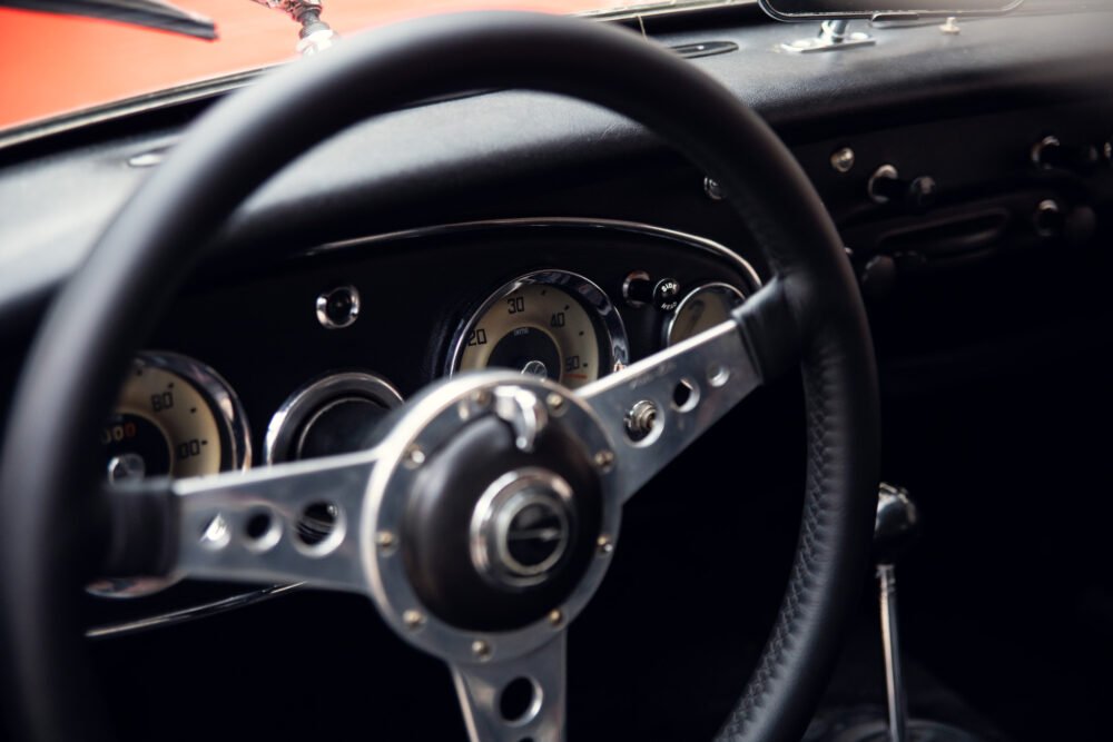 Vintage car dashboard with steering wheel and gauges.