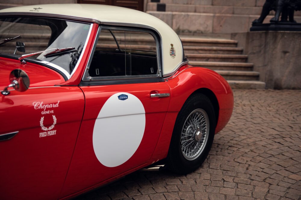 Vintage red sports car with white racing stripes.