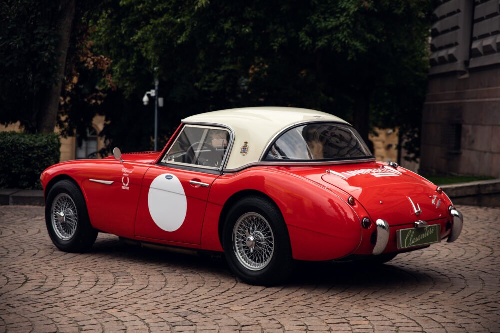 Vintage red sports car with roundel parked on cobblestones