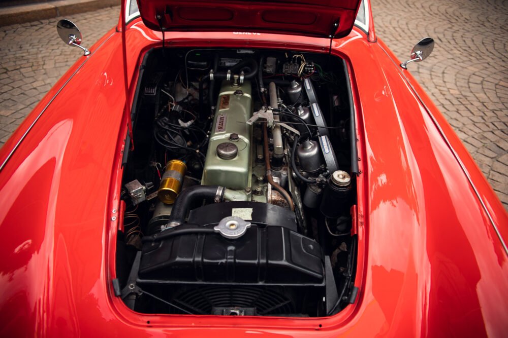 Vintage red car engine compartment open.